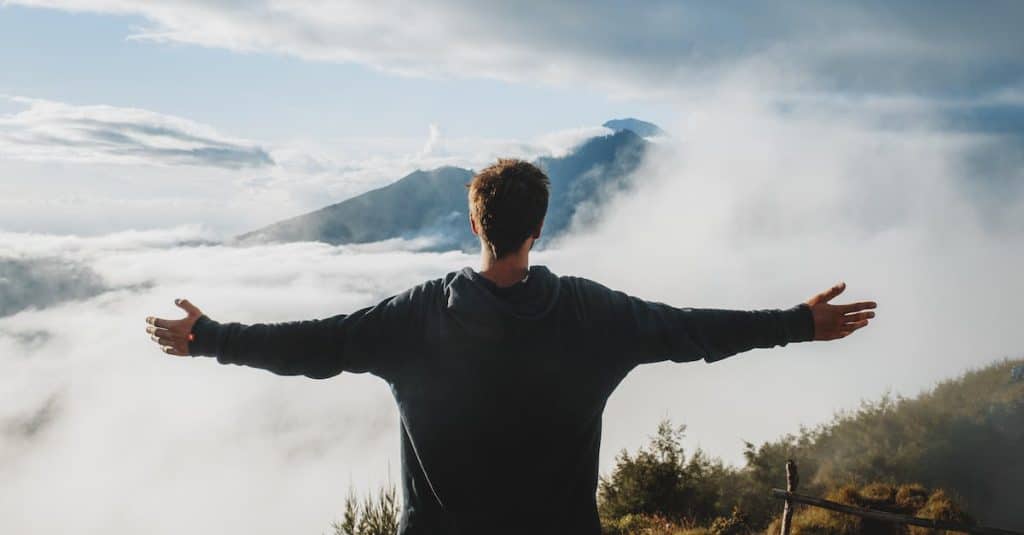 back-view-of-anonymous-male-traveler-in-casual-clothes-standing-on-edge-of-cliff-and-admiring-breath