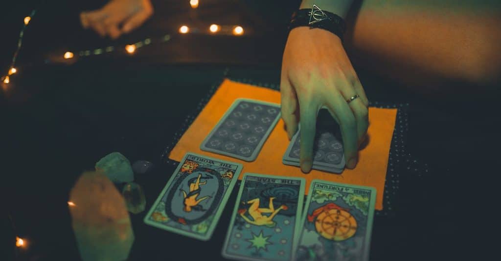 crop-female-future-teller-with-tarot-cards-on-table