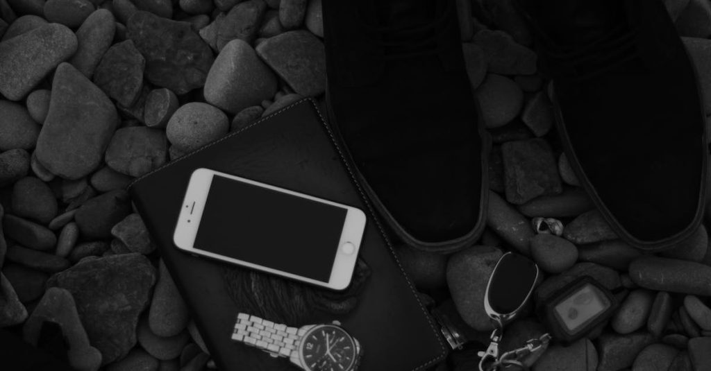 faceless person near smartphone and car key on pebbles