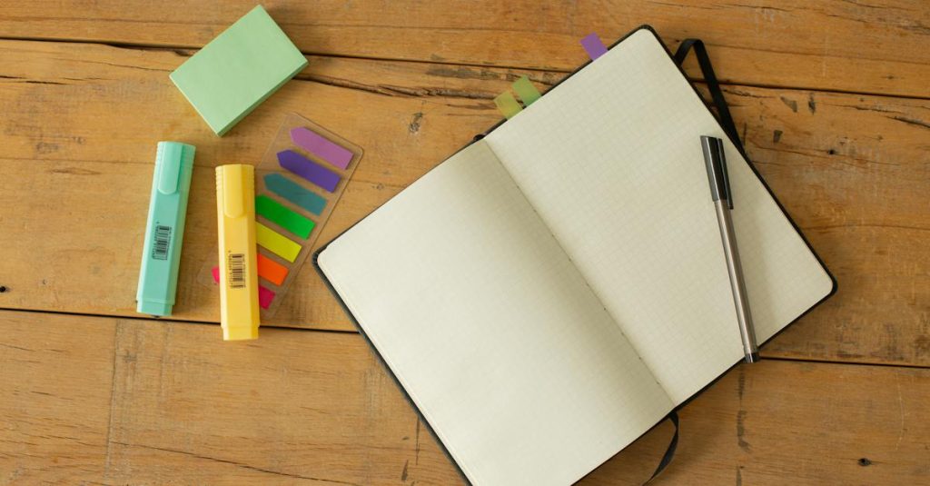 top-view-of-opened-sketchbook-with-blank-pages-and-pen-with-coloured-markers-and-bookmarks-arranged